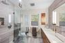 Full bathroom featuring a glass-enclosed shower with a rain showerhead, a built-in shower niche, a wood-finish vanity with an integrated rectangular s