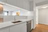 Kitchen featuring stainless steel dishwasher, light stone countertops, white cabinetry, light wood-style flooring, and modern cabinets
