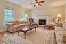Hardwood flooring, white window trim, fireplace with a white mantel, ceiling fan with integrated lighting, and light-colored wall paint