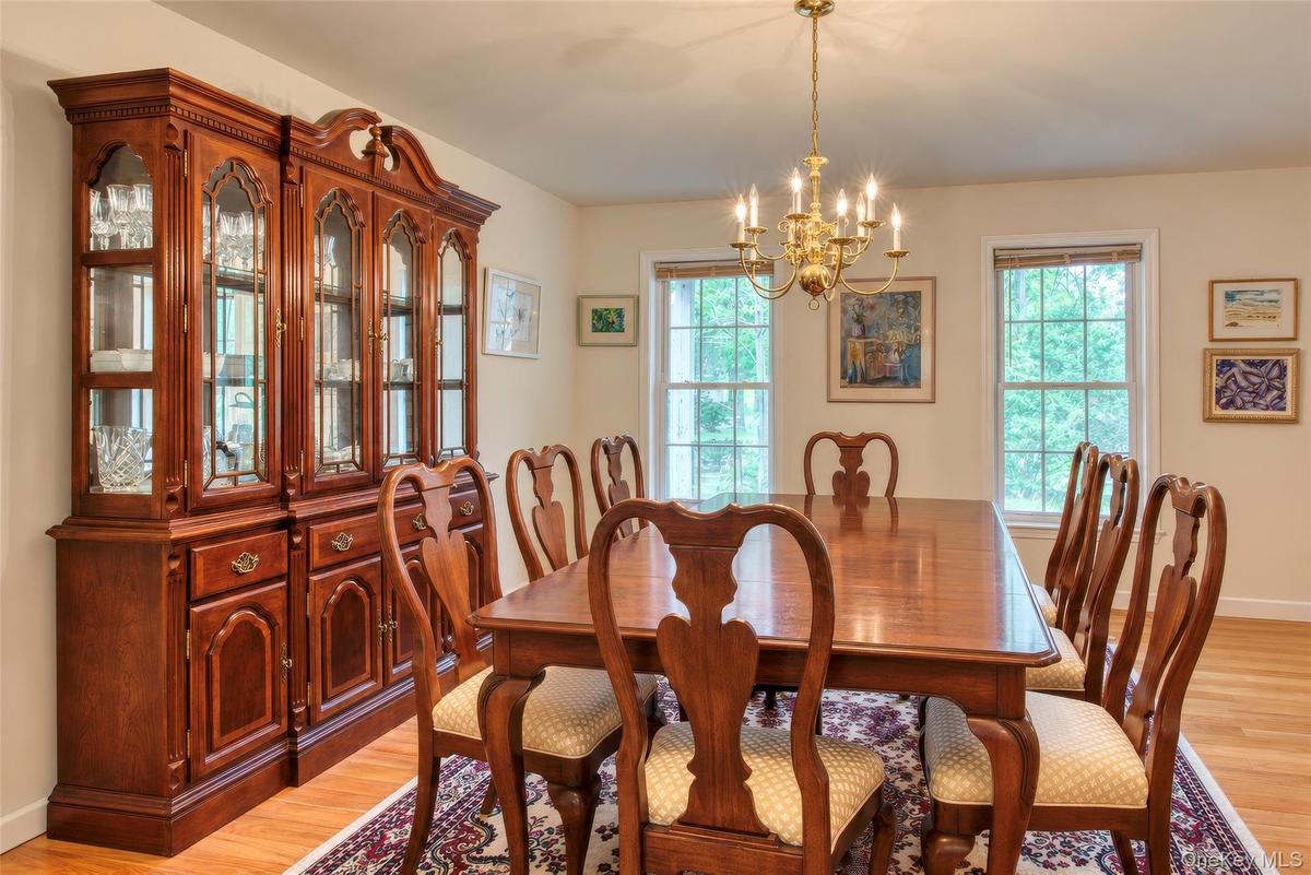 Hardwood flooring, painted walls, multiple windows, and a brass chandelier