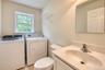 Laundry area with an operable window, built-in vanity with integrated sink, wall-mounted mirror, and tile flooring