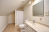 Bathroom featuring tile flooring, single vanity with integrated sink, wall-mounted mirror, and a shower area