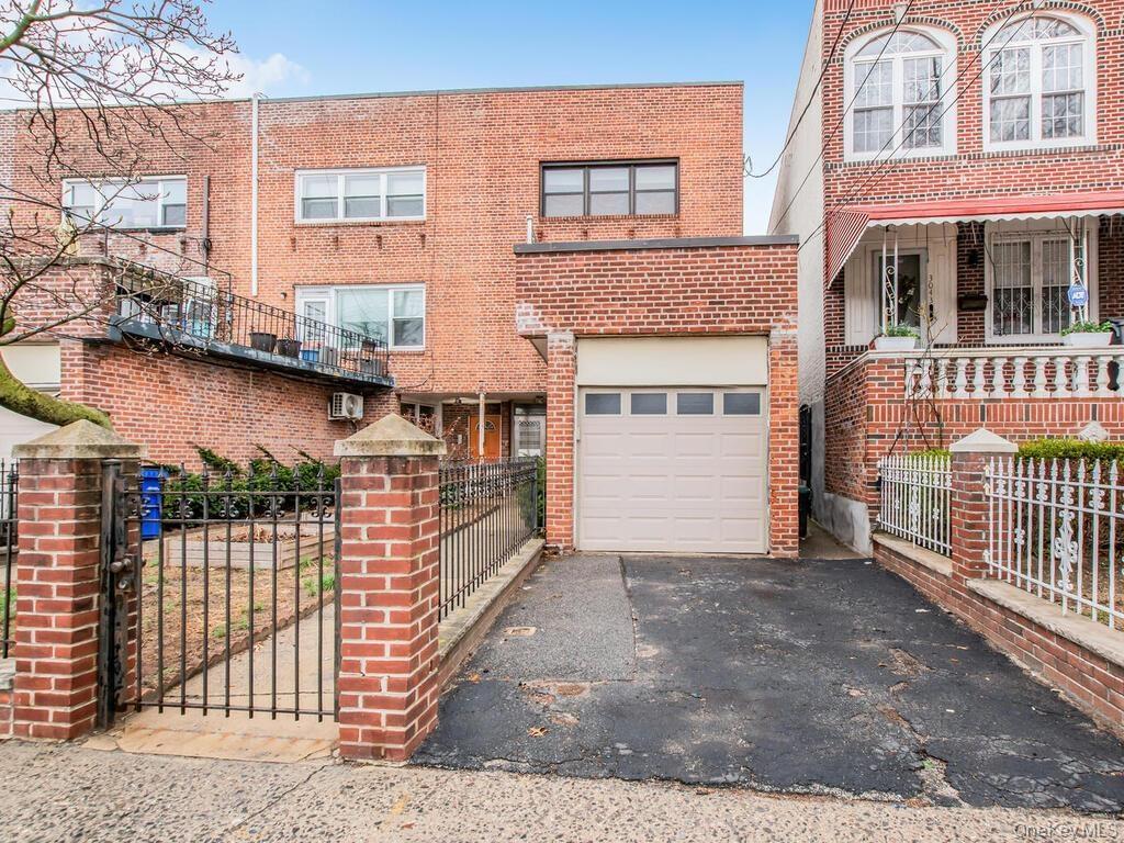 View of front of property featuring brick siding, driveway, an attached garage, and fence