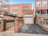 View of front of property featuring brick siding, driveway, an attached garage, and fence