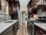 Kitchen with under cabinet range hood, a sink, tasteful backsplash, stainless steel appliances, and light stone countertops