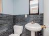 Half bathroom with toilet, tile walls, and wainscoting