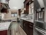Kitchen with a sink, washing machine and dryer, range hood, radiator heating unit, and stainless steel appliances