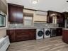 Kitchen featuring backsplash, wood tiled floor, a wall unit AC, appliances with stainless steel finishes, and washer and dryer