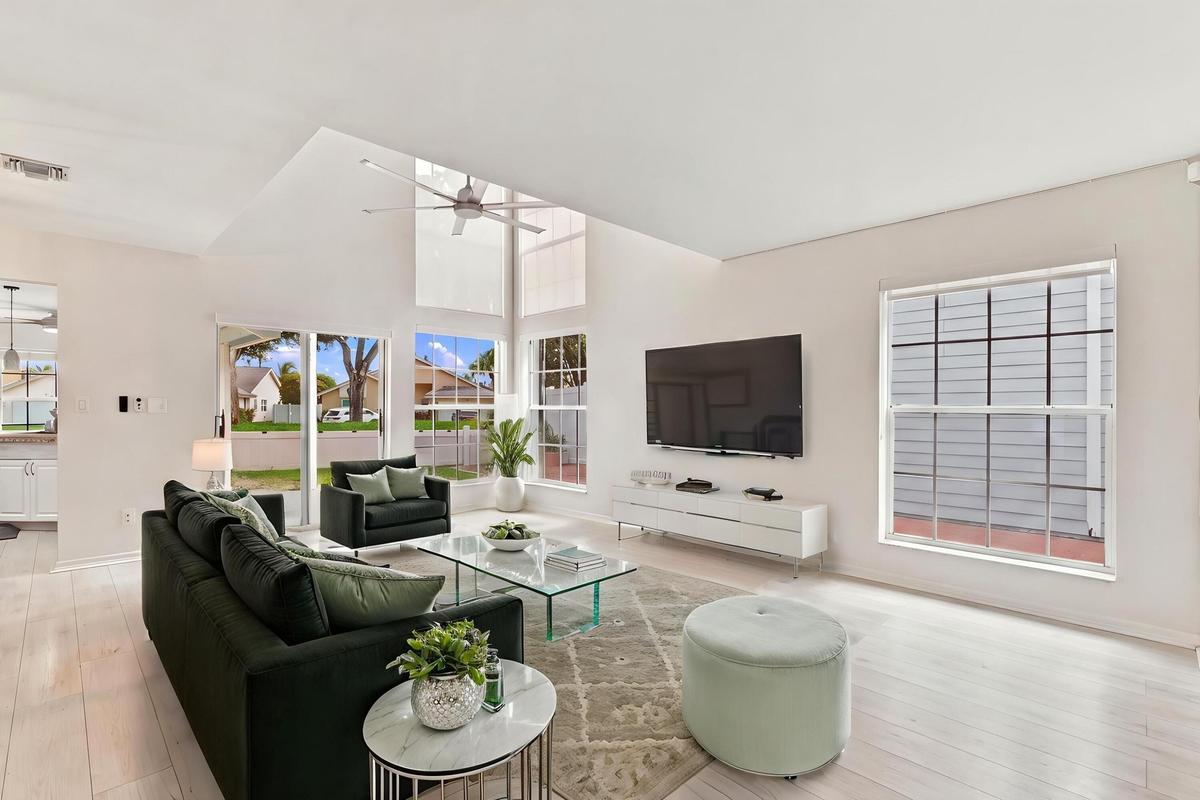 From the moment you enter, soaring ceilings and expansive windows fill the home with natural light, creating a bright, welcoming atmosphere that immed