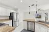 The bright eat-in kitchen features contemporary white cabinetry, granite countertops, new stainless steel appliances, and a convenient breakfast bar. 