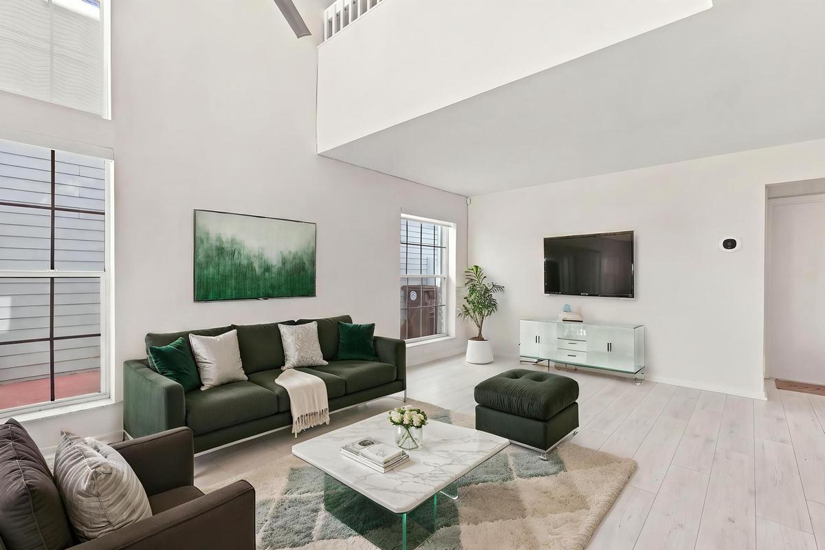 Soaring 15-foot ceilings and expansive windows fill the living room with natural light, creating a warm and welcoming space for everyday living and en