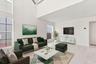 Soaring 15-foot ceilings and expansive windows fill the living room with natural light, creating a warm and welcoming space for everyday living and en