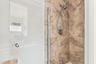 The fully updated primary ensuite exudes refined elegance with a natural oak vanity, quartz countertops, new fixtures, a relaxing bathtub, and a beaut