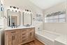 The fully updated primary ensuite exudes refined elegance with a natural oak vanity, quartz countertops, new fixtures, a relaxing bathtub, and a beaut