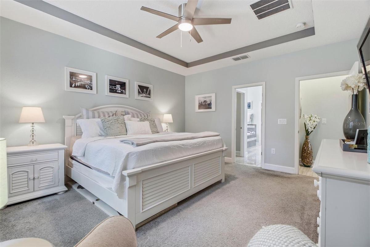 Primary bedroom with ceiling fan and two windows for natural light