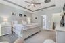 Primary bedroom with ceiling fan and two windows for natural light