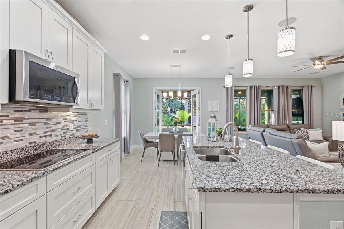 Gourmet kitchen anchored by a large island with seating for three and glass French doors leading to the patio
