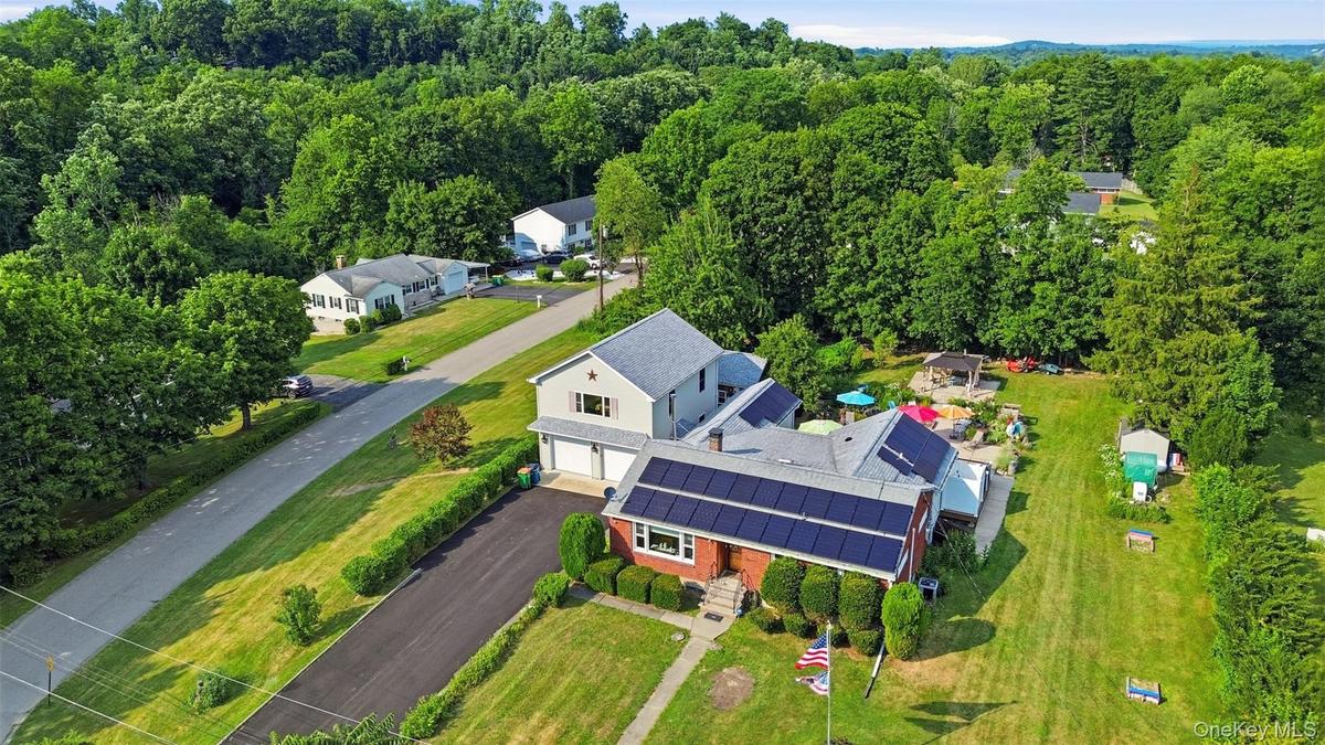 Expansive property featuring a brick and siding exterior, solar panel installation, attached two-car garage, and a substantial green lawn