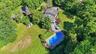 Expansive property featuring a large in-ground pool, extensive paved patio, substantial green space, mature trees, and a detached storage shed