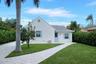 White stucco exterior with a gray shingle roof, blue shutters, and a matching blue entry door