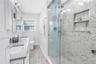 Primary bath with designer shower with spa stones and Art Deco influenced sand and sea aesthetic and built- in shower niche.