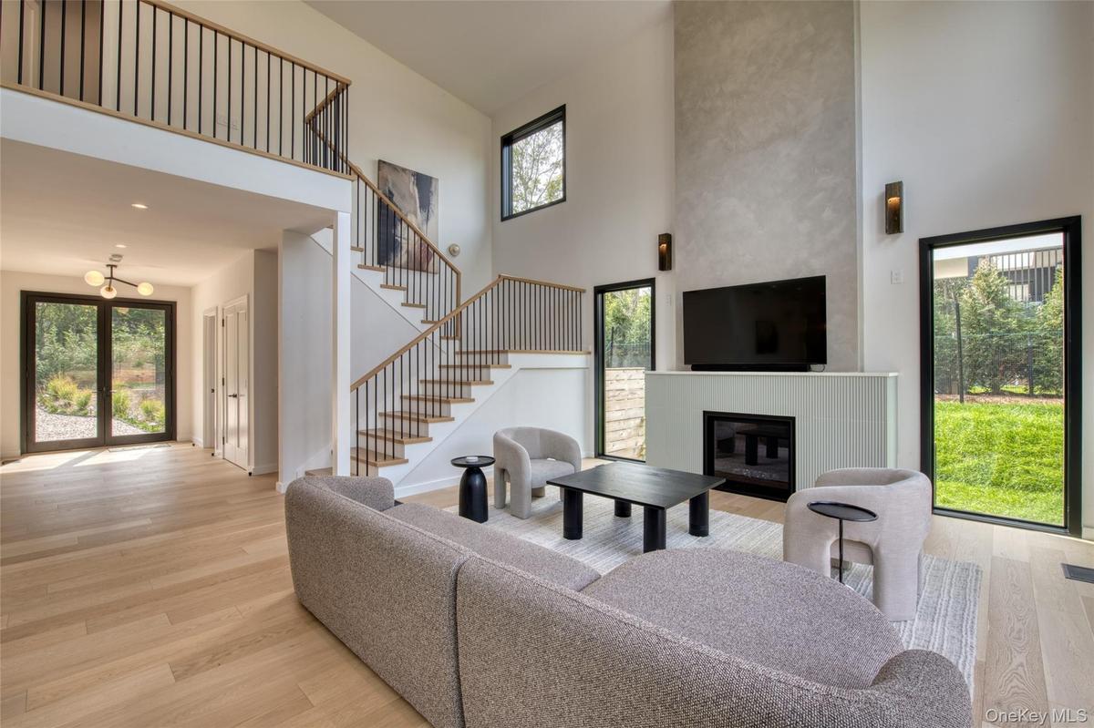 Two-story living area with wood-finish flooring, a contemporary fireplace, and a light-filled interior