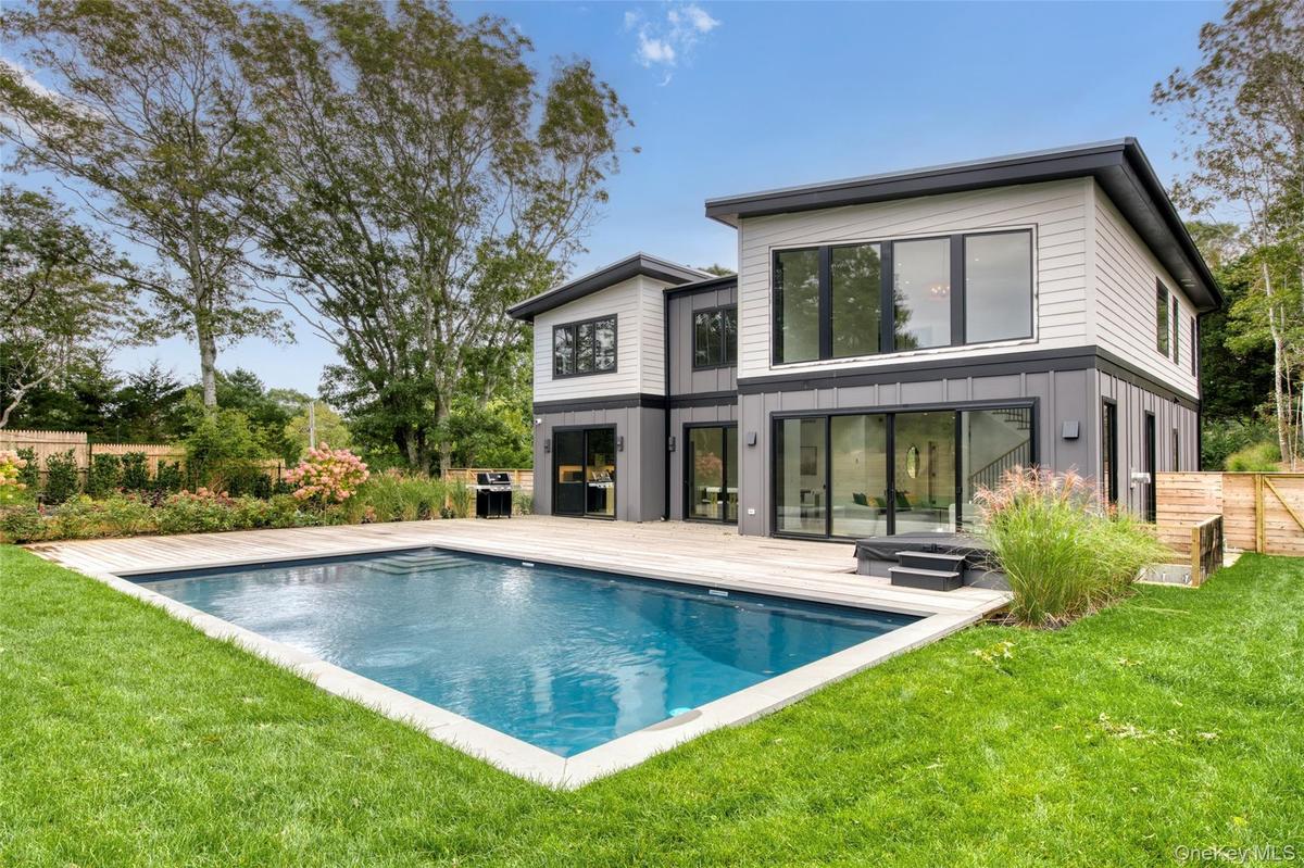 Modern residence featuring an in-ground swimming pool, spa, expansive wood-finish deck, and large sliding glass doors