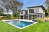 Modern residence featuring an in-ground swimming pool, spa, expansive wood-finish deck, and large sliding glass doors