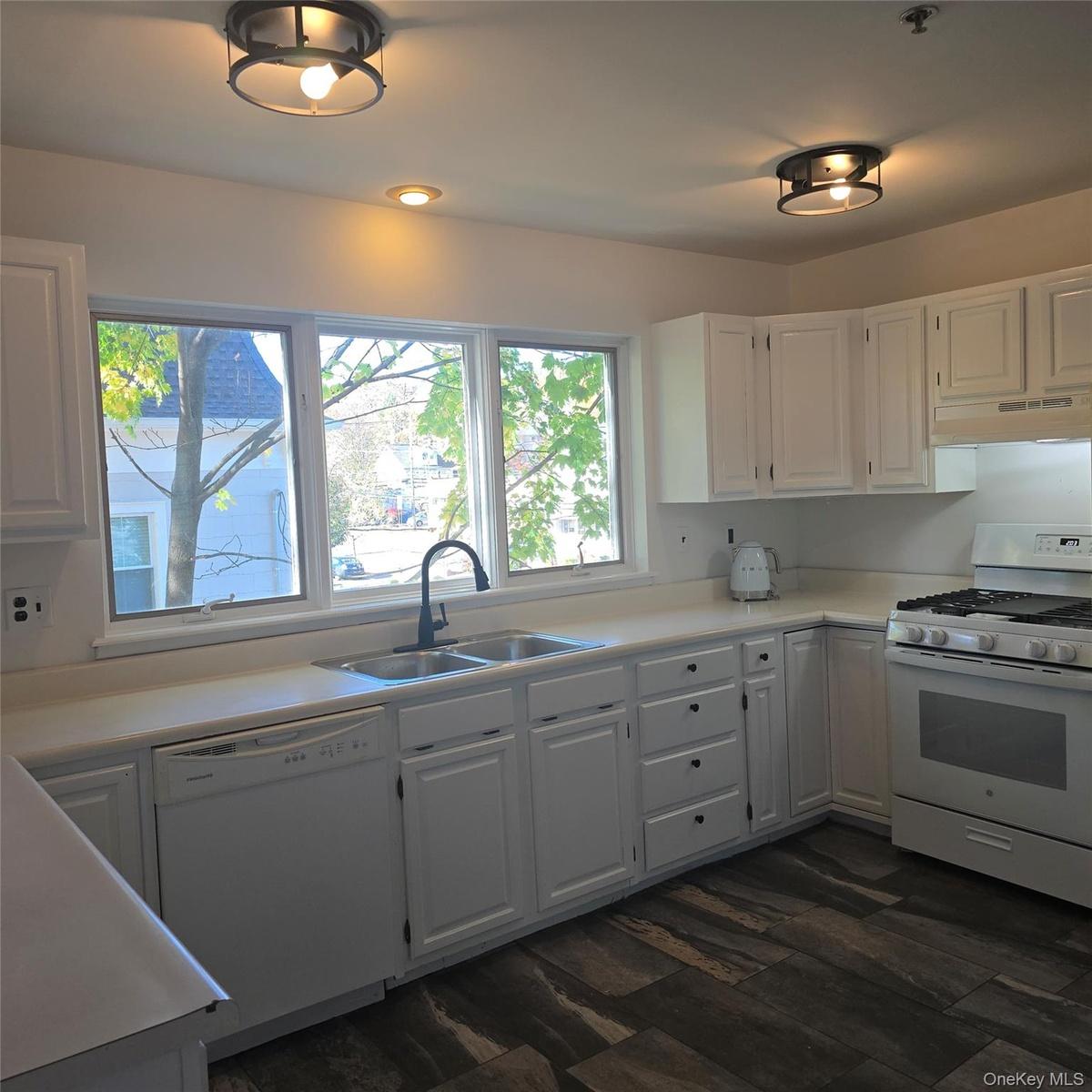 Kitchen with white cabinetry, extractor fan, dark hardwood / wood-style floors, sink, and white appliances