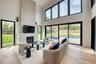 Two-story living area with high cathedral ceilings, featuring a built-in fireplace, large format windows, and wood-finish flooring