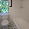 Bathroom with tile patterned floors, toilet, a tub, and tile walls