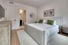 Light wood-finish flooring, white walls, and a private bath featuring a dark wood vanity and round mirror