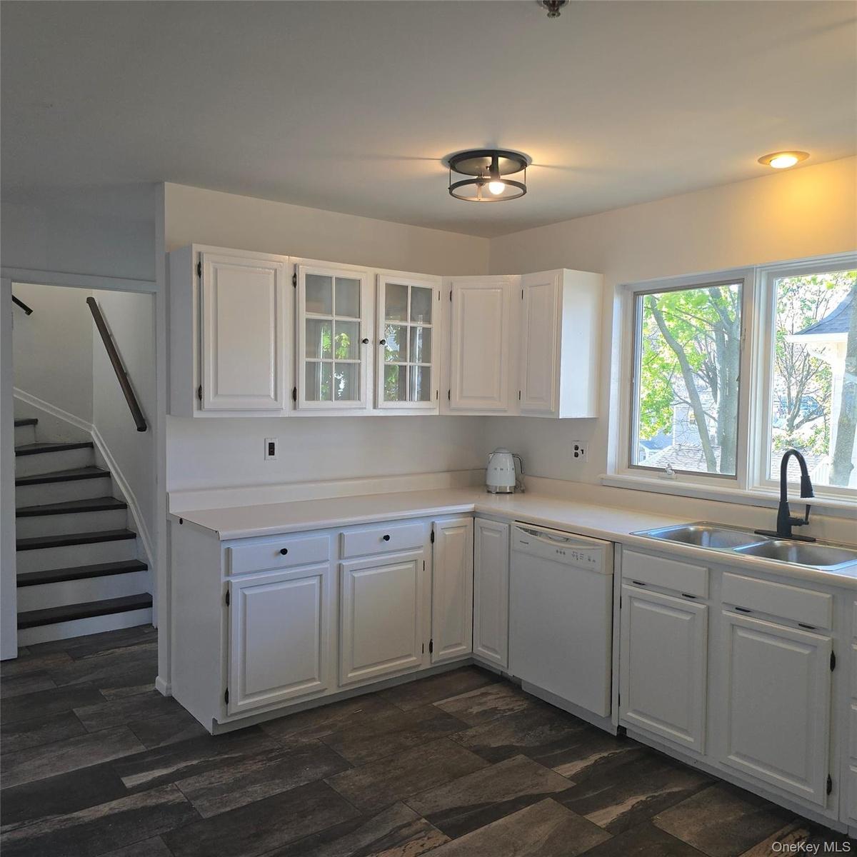 Kitchen with white dishwasher, dark hardwood / wood-style floors, white cabinetry, and sink
