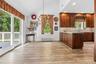 Varnished wood-finish flooring, vaulted ceiling, built-in recessed lighting, wood cabinetry with countertop, and sliding glass door to exterior deckin