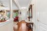Hardwood flooring, decorative columns, crown molding, transom window above entry, and a ceiling fan