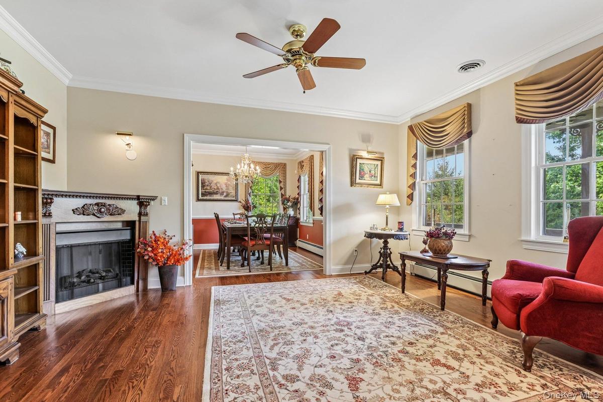 Hardwood flooring, decorative fireplace, crown molding, and a ceiling fan with integrated lighting