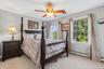 Carpeted bedroom with two large windows, a ceiling fan, and light gray wall paint