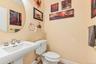 Pedestal sink with chrome fixtures, round wall-mounted mirror, and white toilet