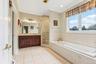 Dual vanity with integrated sinks, a built-in soaking tub, and a glass-enclosed shower