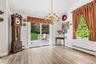 Light wood-finish flooring with a multi-pane window, brass chandelier, and a sliding glass door opening to an outdoor deck