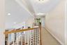 Carpeted hallway with flush-mount lighting, wood handrails, and white balusters