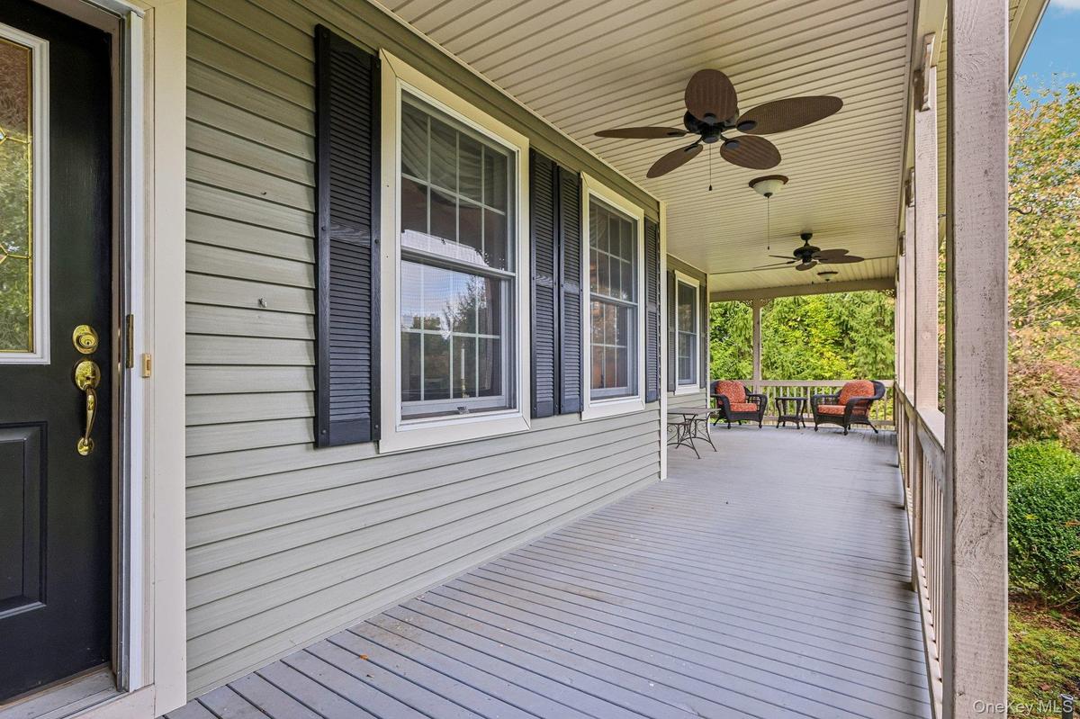 Expansive covered porch featuring ceiling fans, light-toned siding, and dark window shutters