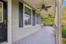 Expansive covered porch featuring ceiling fans, light-toned siding, and dark window shutters