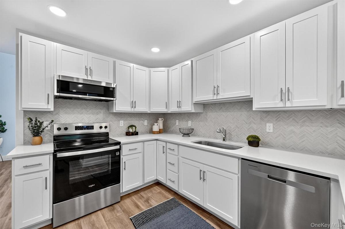 Kitchen featuring stainless steel appliances, white cabinets, light wood-style floors, tasteful backsplash, and recessed lighting