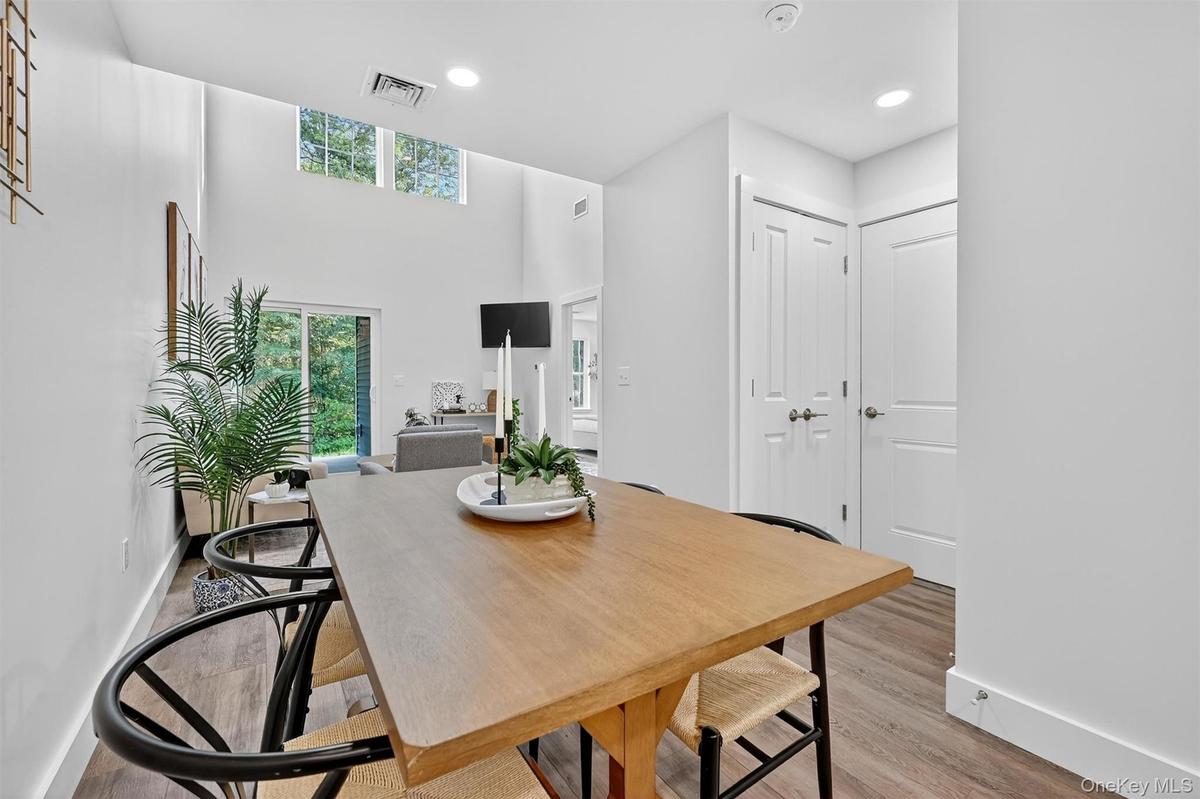 Dining room with wood finished floors, recessed lighting, and a high ceiling