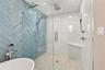 Spa-inspired glass-enclosed shower with a rainfall showerhead and handheld wand.