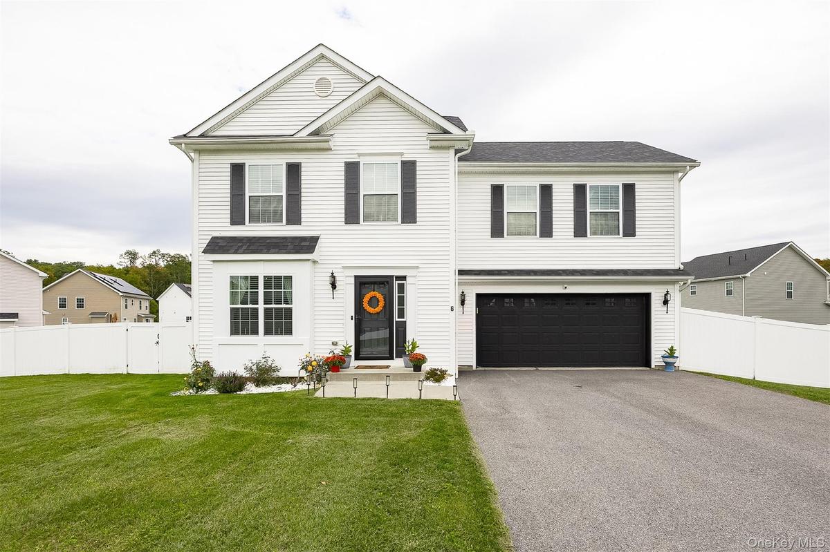 Two-story residence featuring white siding, black shutters, a two-car garage, and a fenced backyard