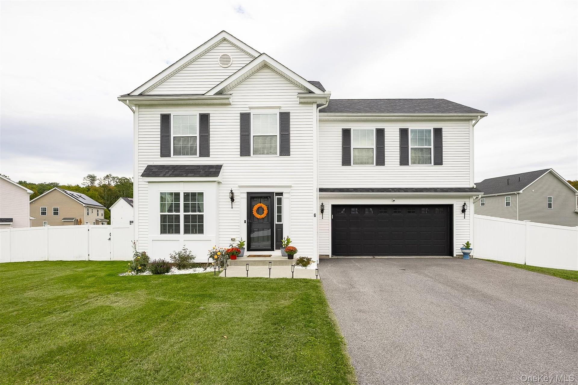 Two-story residence featuring white siding, black shutters, a two-car garage, and a fenced backyard