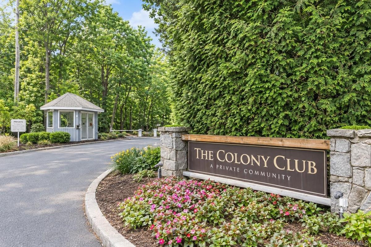 Virtually Edited. Entry sign "The Colony Club a Private Community" with stone pillars and mature evergreen landscaping.