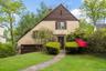 View of front of property with a chimney, stone siding, a front yard, and stucco siding